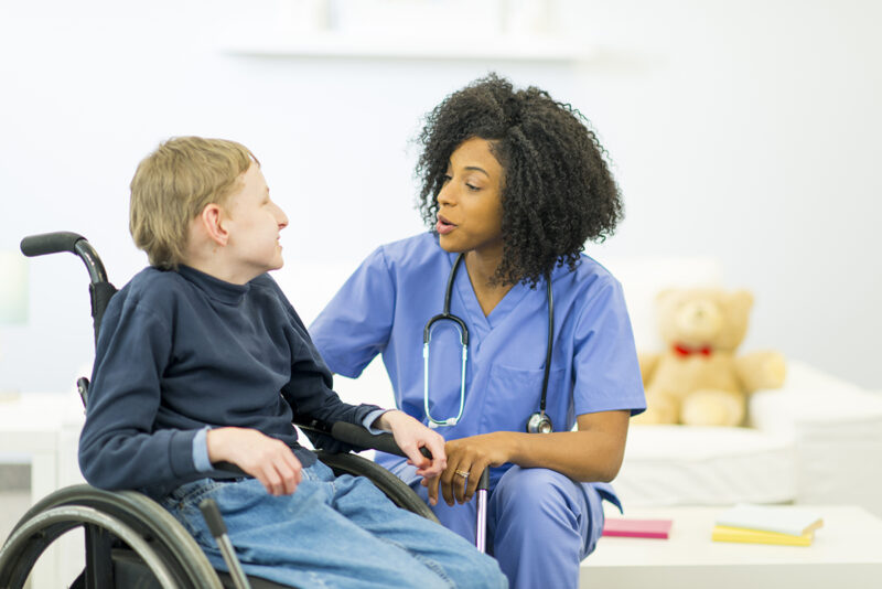 black female nurse helping a boy with a developmental disability